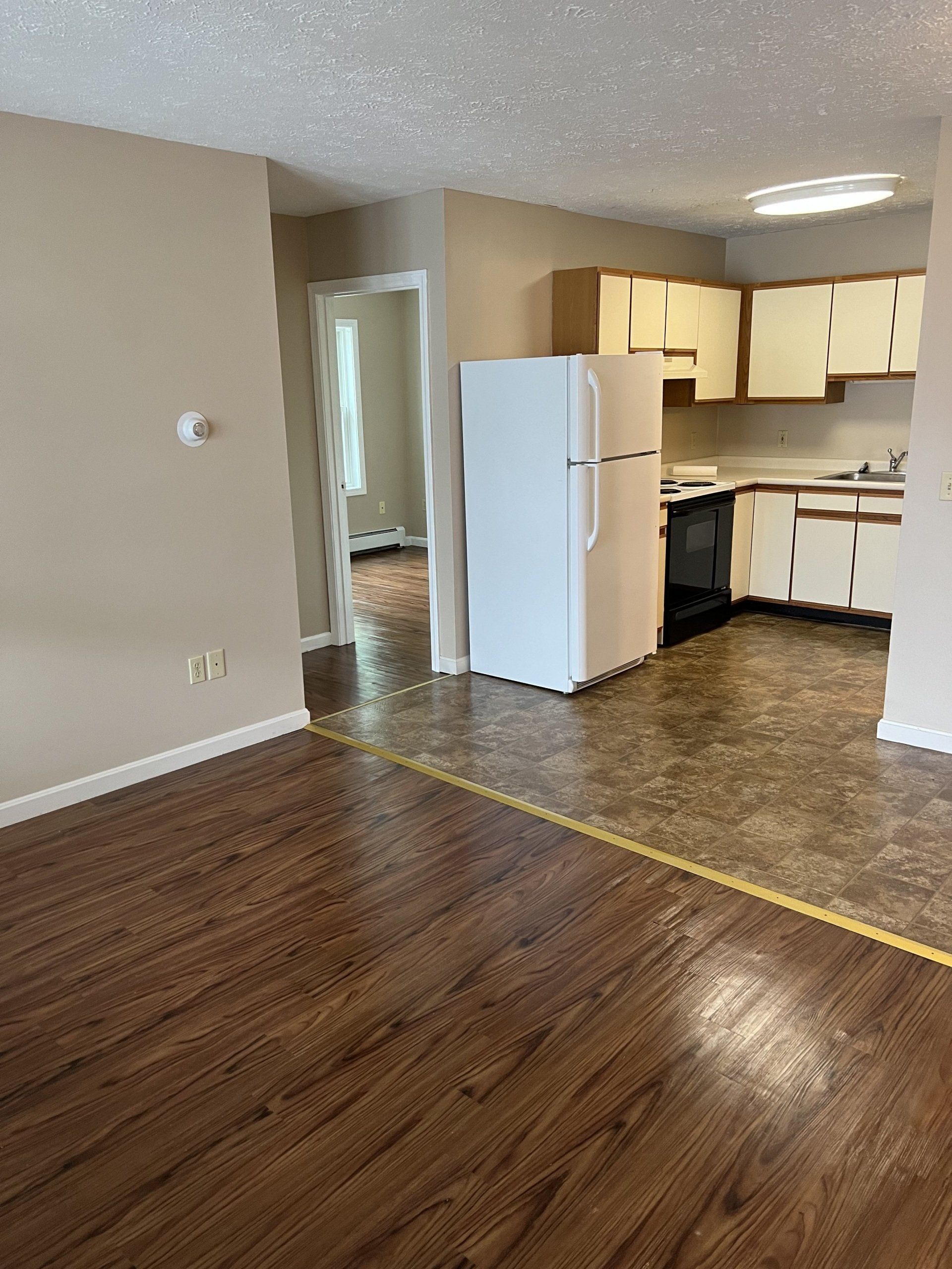 8c Church St. - living room with wood flooring and view of kitchen with refrigerator