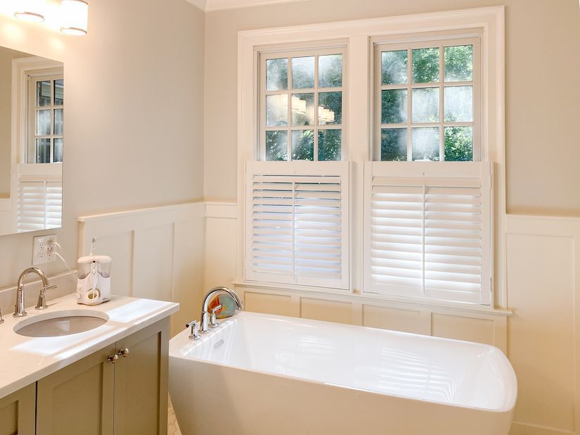 Cafe style plantation shutters above a floating tub in a bathroom