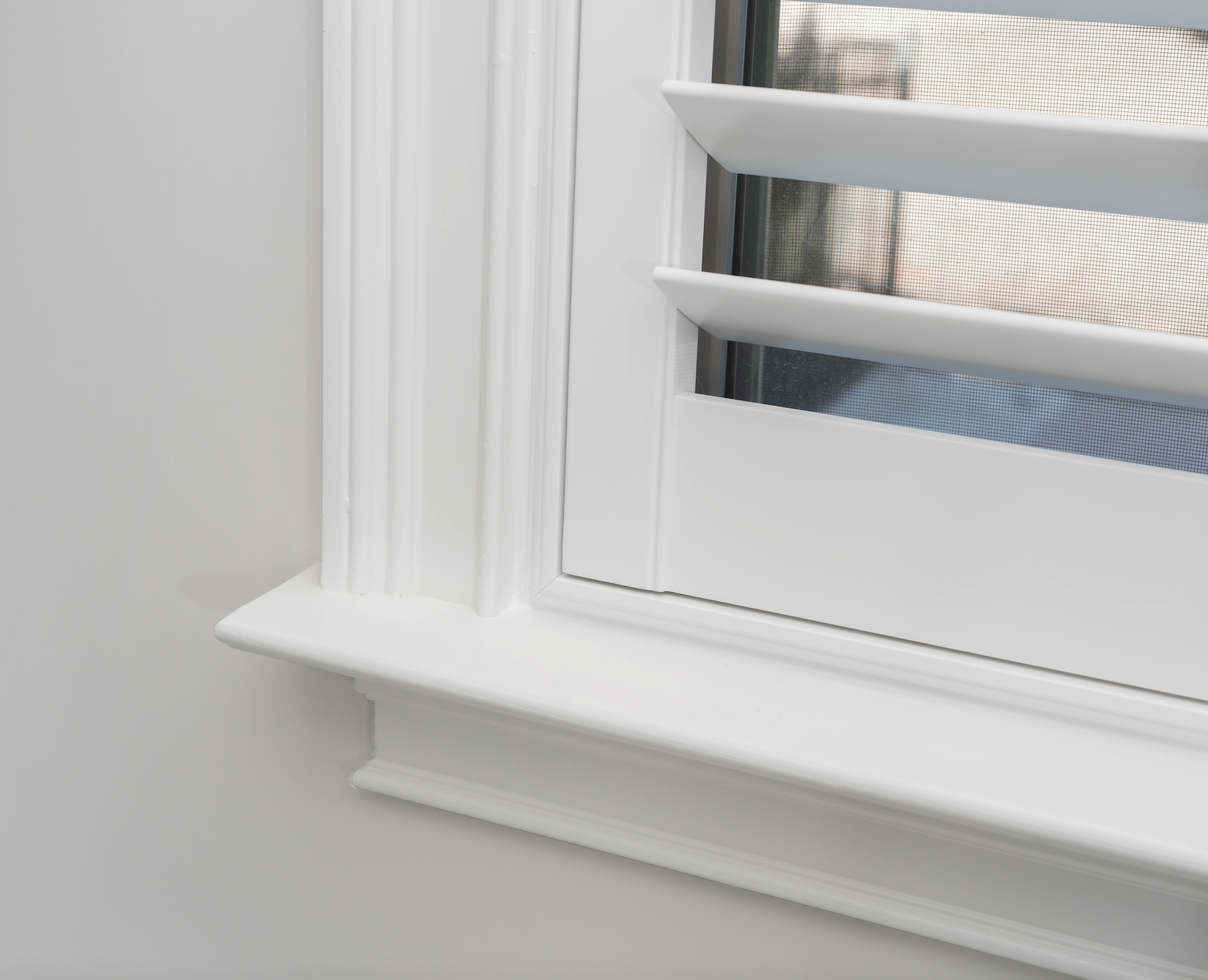 A close up of an inside mount plantation shutter on a window with large RB3 trim casing
