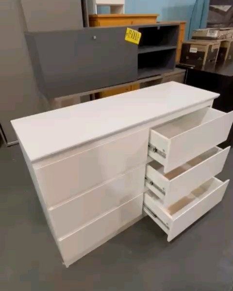Cómoda blanca con tres cajones abiertos, puesta en almacén.