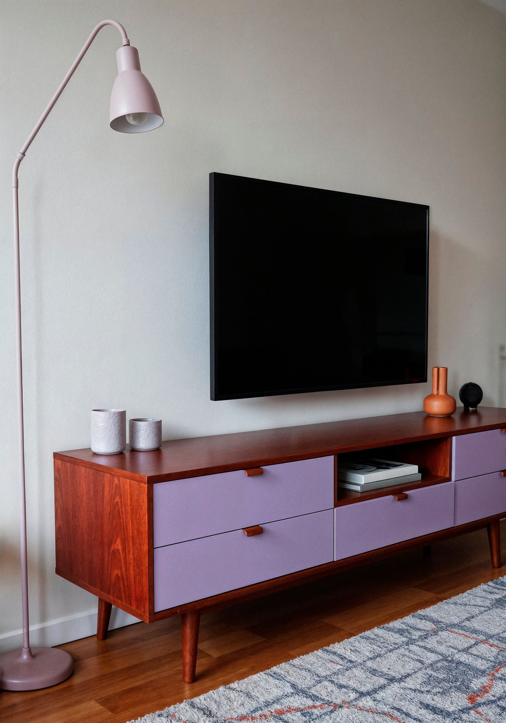 Una sala de estar con un centro de entretenimiento morado y un televisor de pantalla plana en la pared.