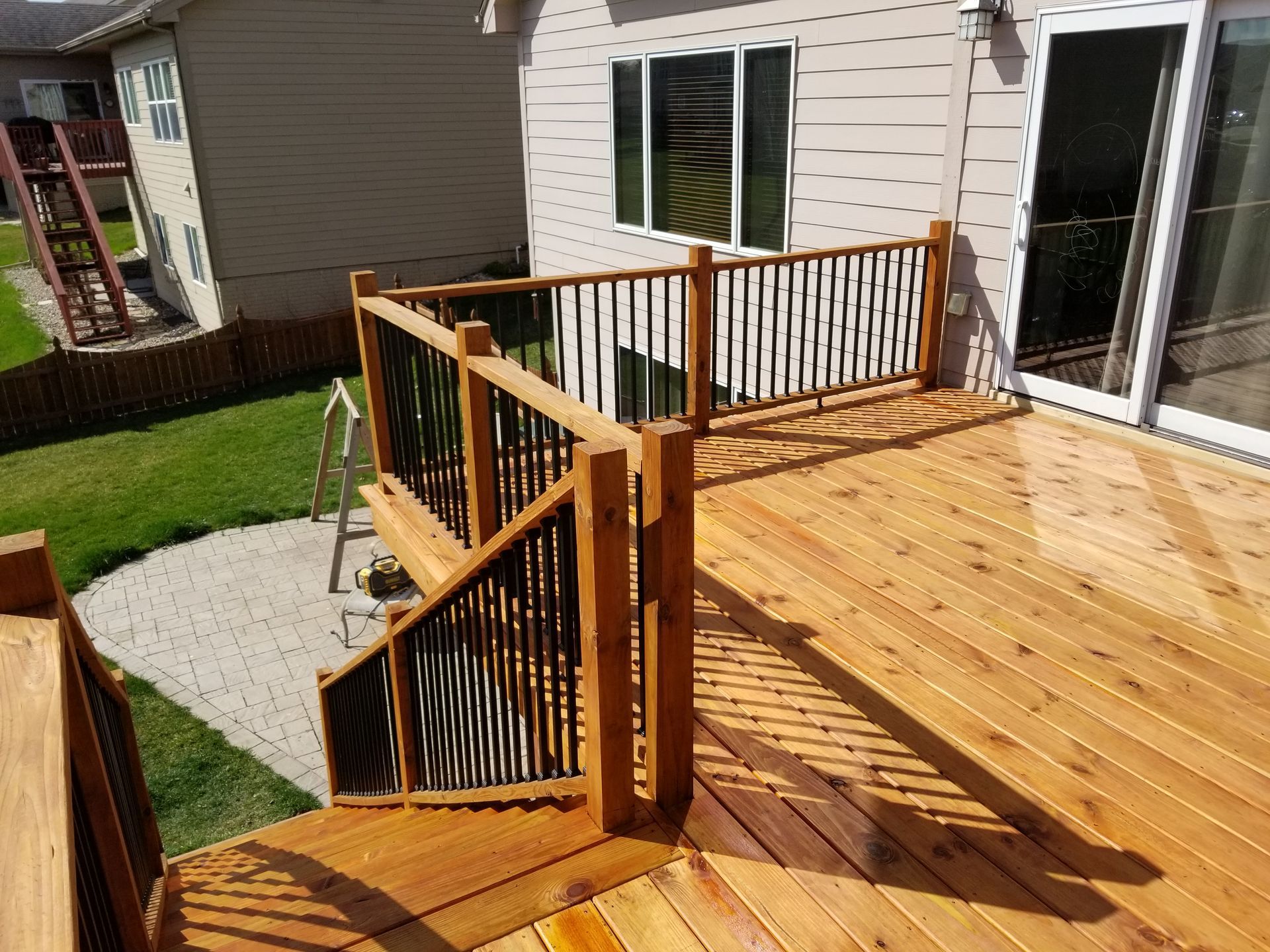 A wooden deck with stairs leading up to it and a house in the background