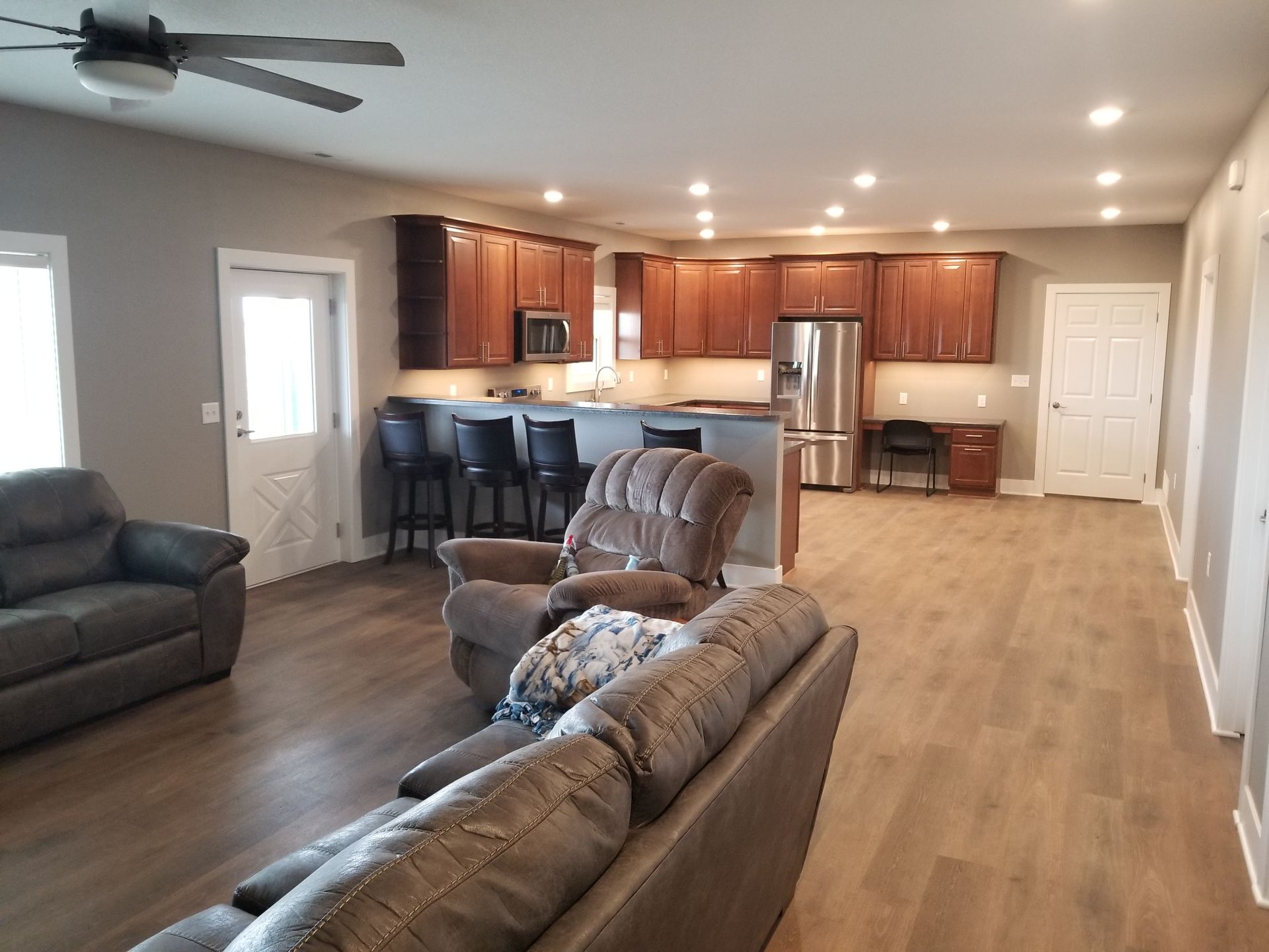 A living room with a couch , chairs , and a ceiling fan.