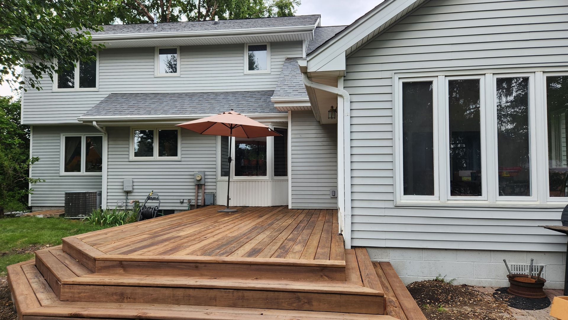 A white house with a wooden deck and stairs in front of it.