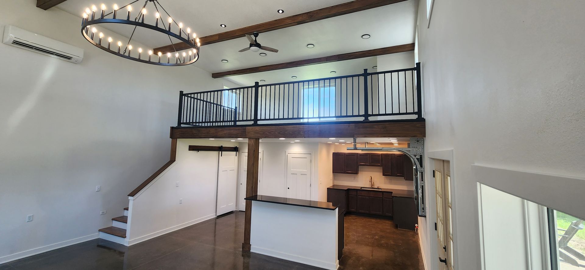 A large empty room with a balcony and stairs in a house.