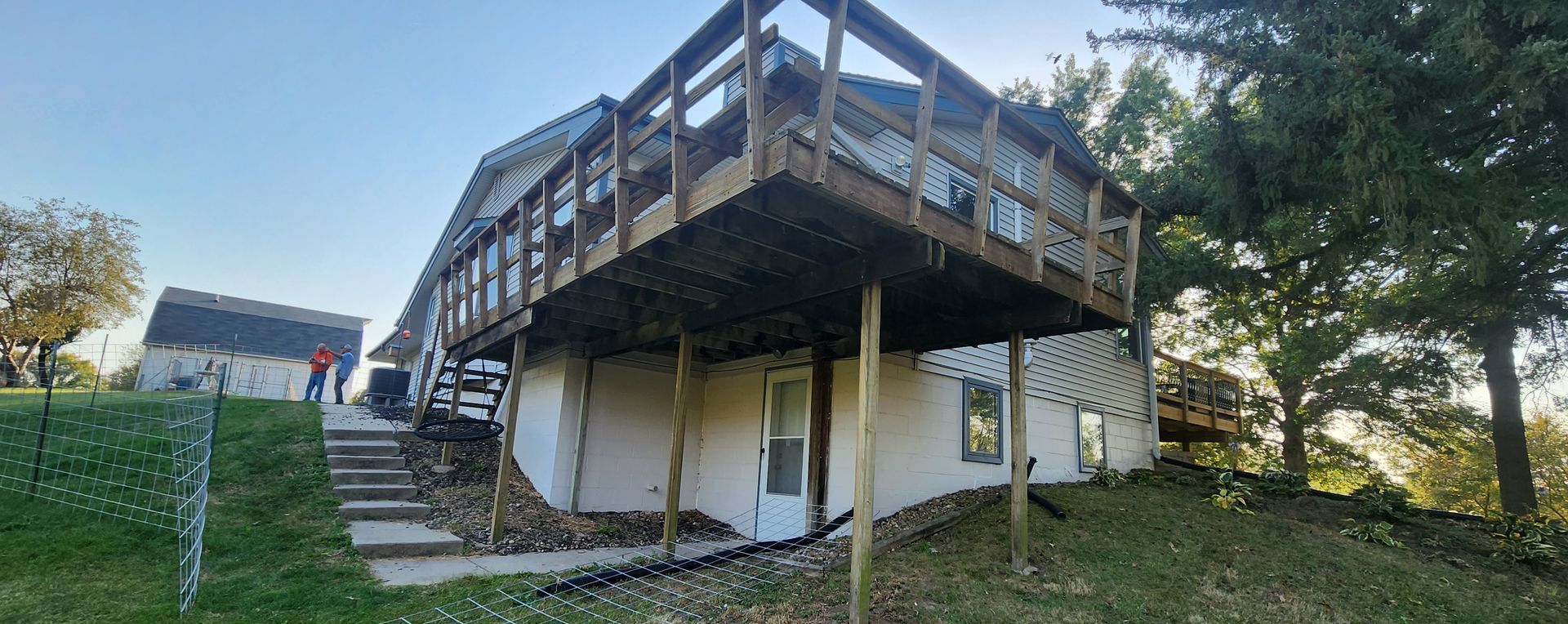 A house with a large wooden deck on top of it.