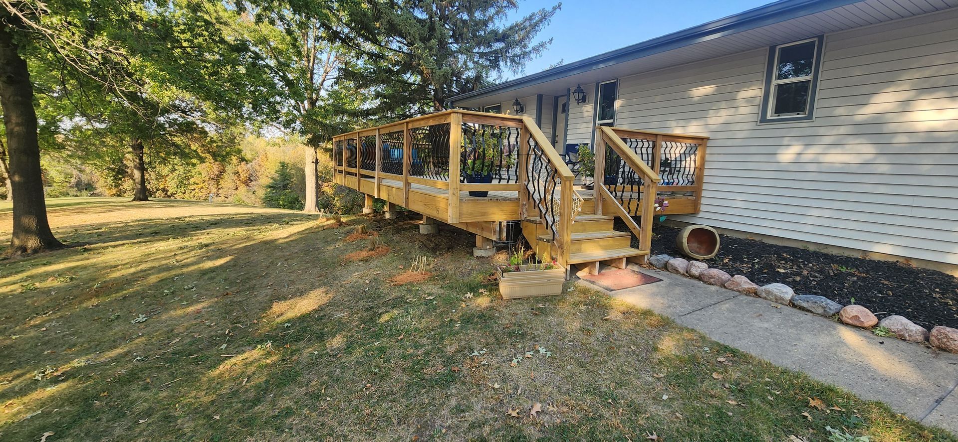 A white house with a wooden deck and stairs in front of it.