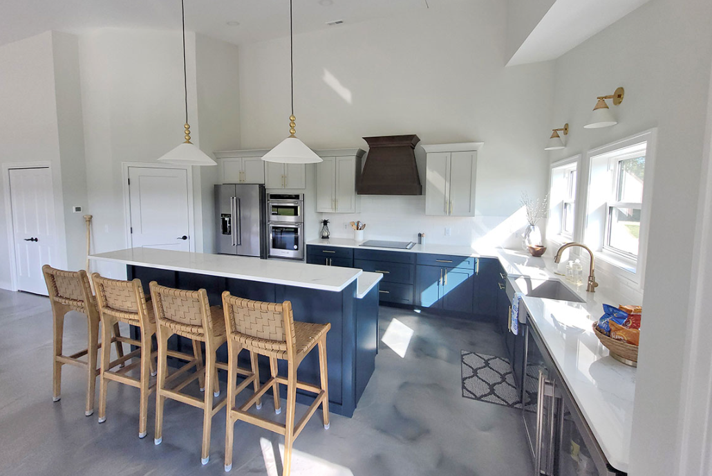 A kitchen with a large island , stools and a refrigerator.