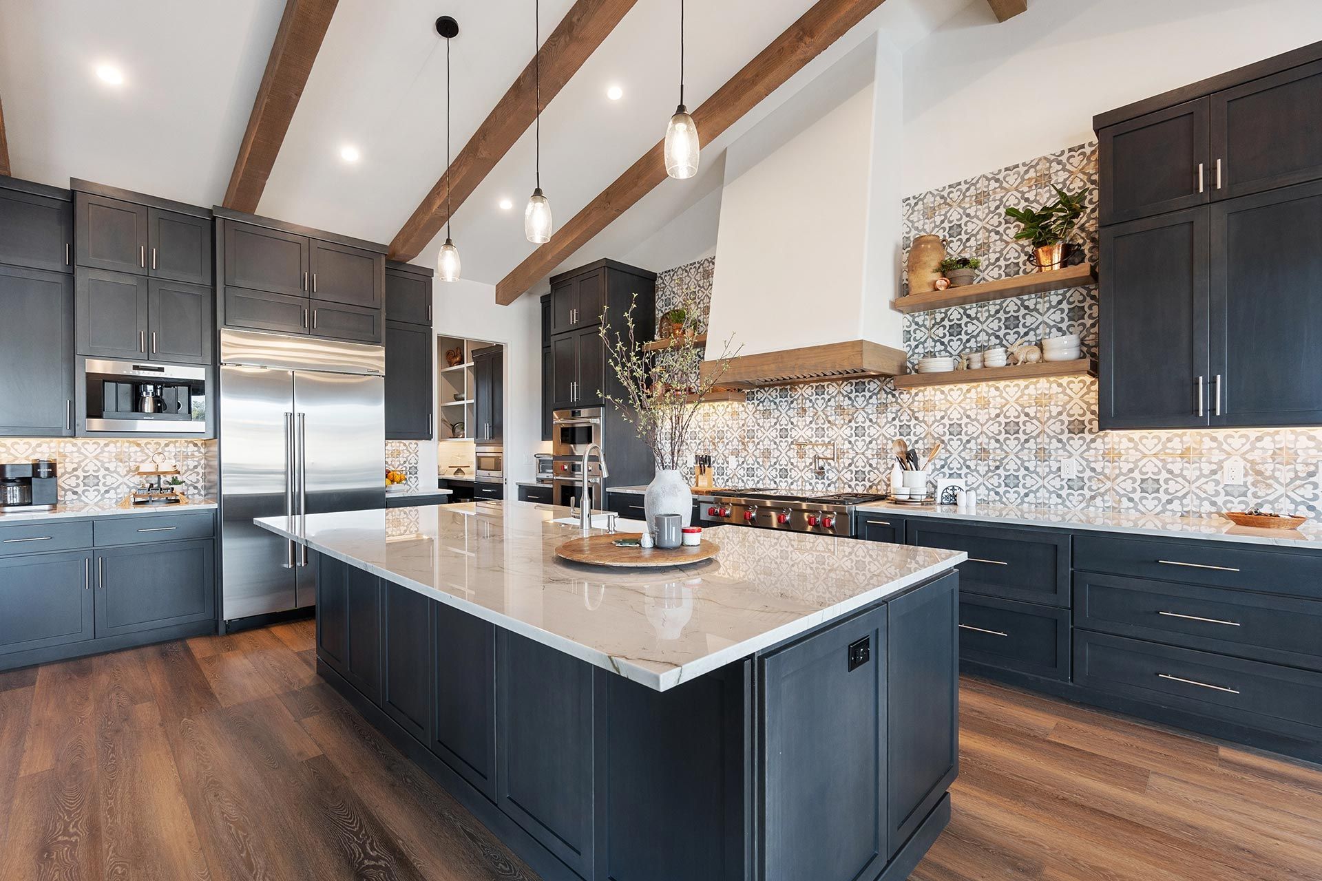 Spacious modern kitchen with dark cabinets, marble island, and patterned tile backsplash.