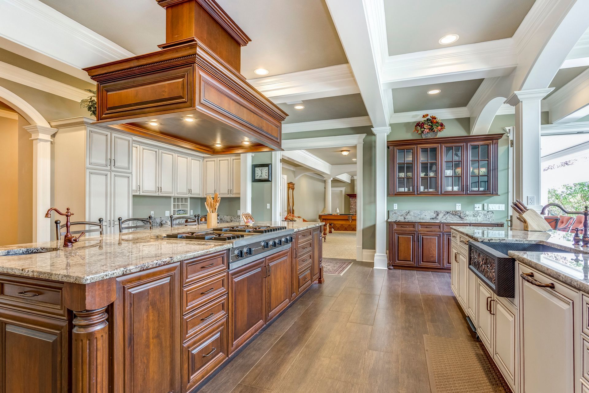 Modern kitchen with wood cabinets, marble counters, stainless appliances, island, and pool table.