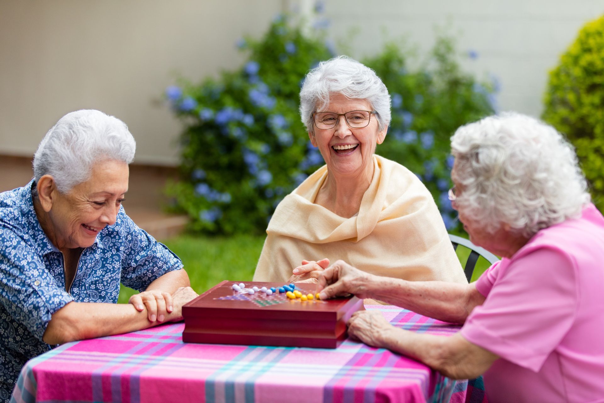 Cheerful elderly women enjoying a board game outdoors at an Assisted Living Center in Bealeton, VA.]