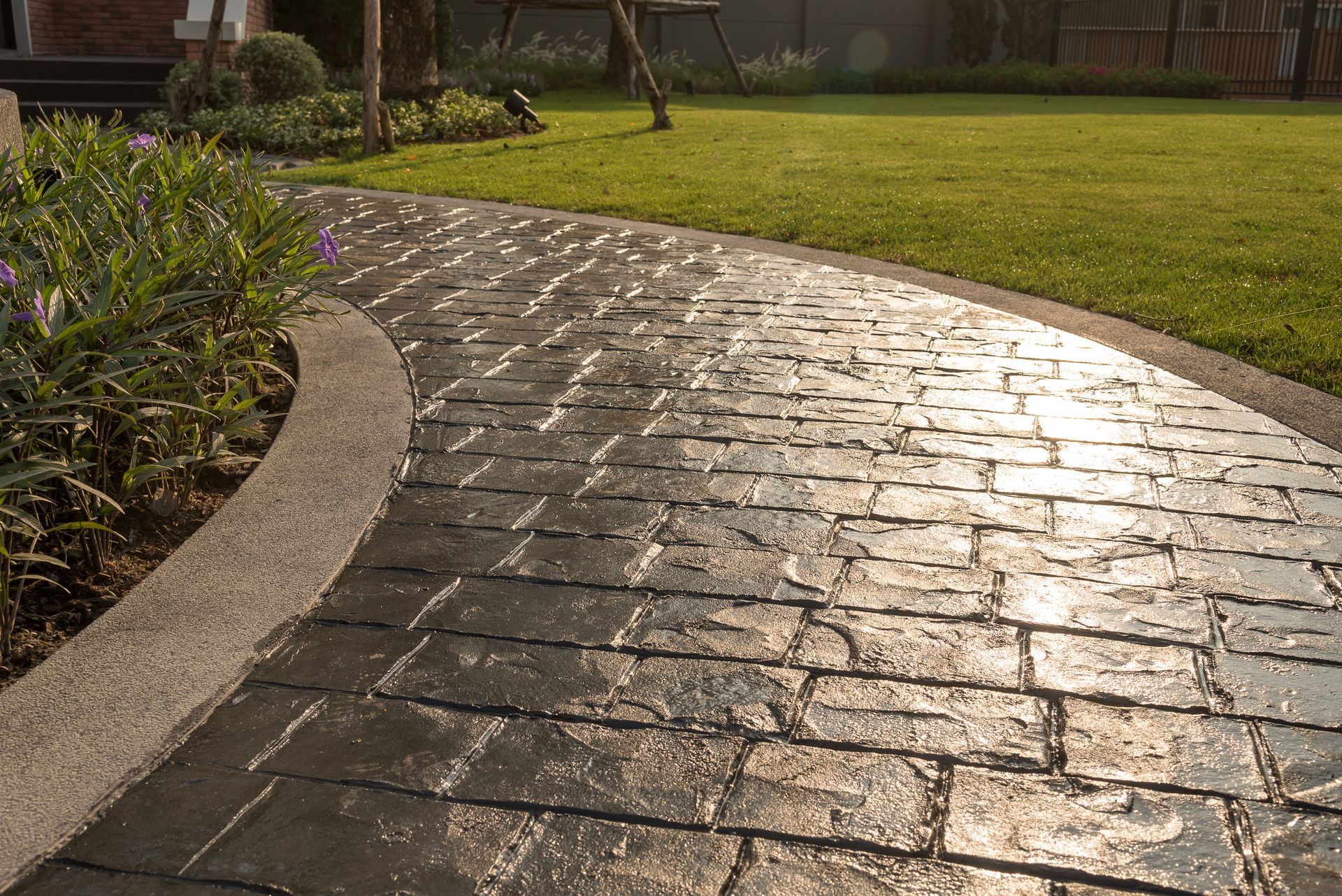 A brick walkway leading to a lush green lawn.