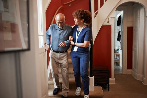 A nurse is helping an elderly man walk up the stairs.