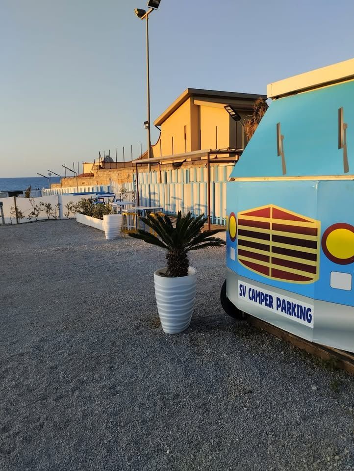 A blue camper parked next to a potted plant