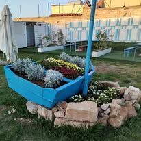 A blue boat full of flowers and rocks in a garden.