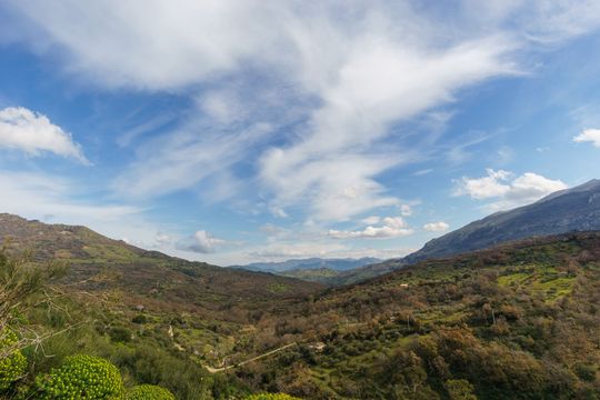 Una vista di una valle con montagne sullo sfondo e nuvole nel cielo.