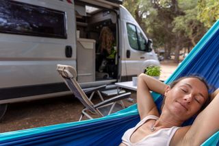 Una donna dorme su un'amaca davanti a un camper.