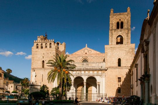 Un grande edificio con un campanile e delle palme di fronte