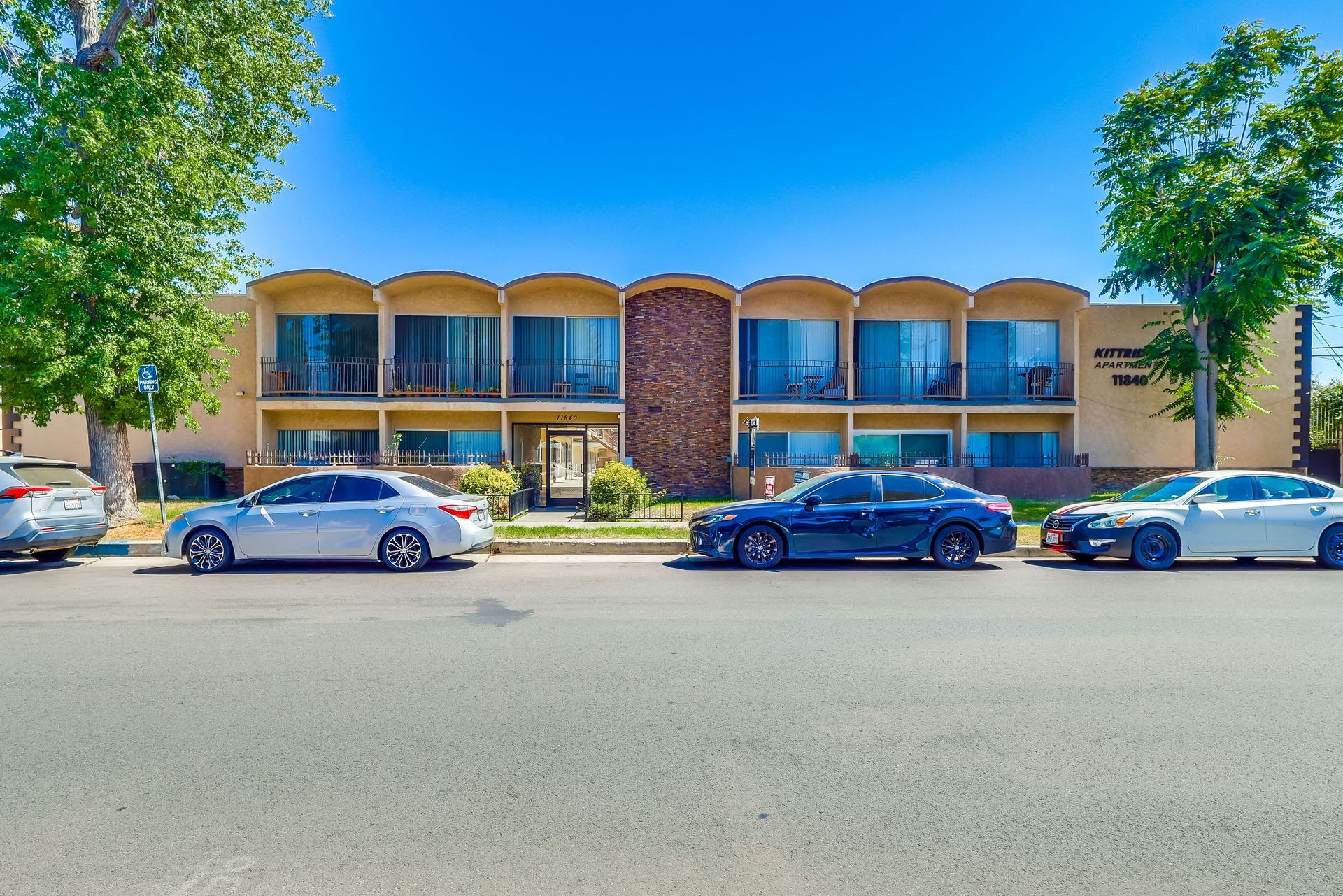 A row of cars are parked in front of a building.