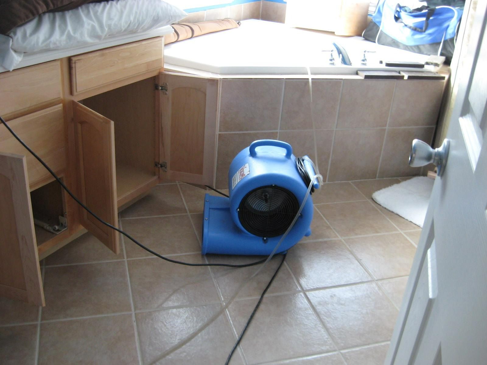 Blue air mover in a bathroom with cabinets and a tub.