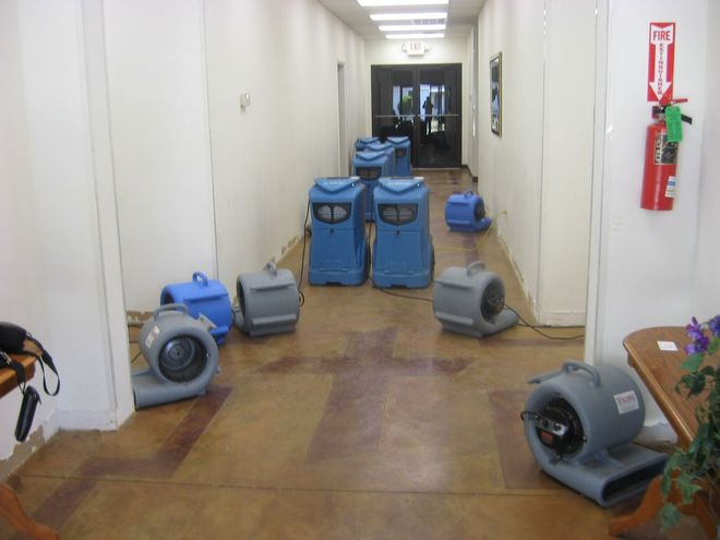 Hallway with several blue and gray air movers, likely for drying after water damage.