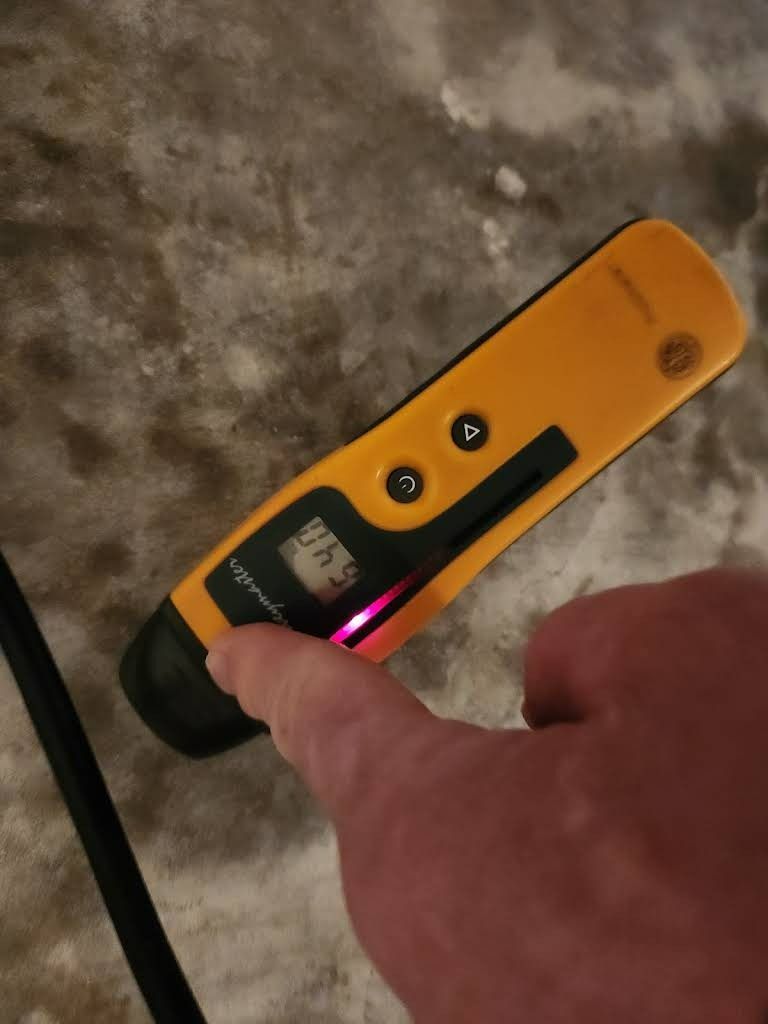 A person holding a yellow electrical tester; pressing the button. The tester shows a red light.