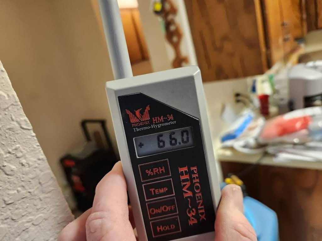 Hand holding a gray Phoenix HM-34 meter displaying 