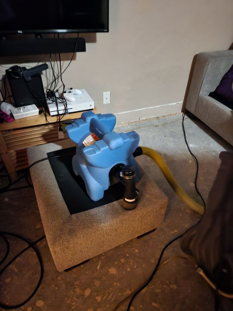 Blue dehumidifier on an ottoman in a room with entertainment system and couch.