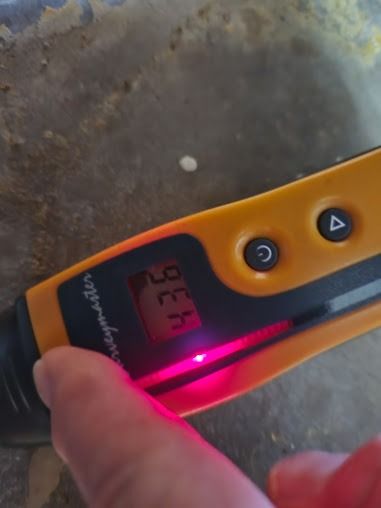 A hand holding a yellow voltage tester. The display reads 32 A with a red light illuminated.