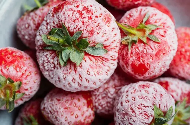 A close up of frozen strawberries in a bowl.