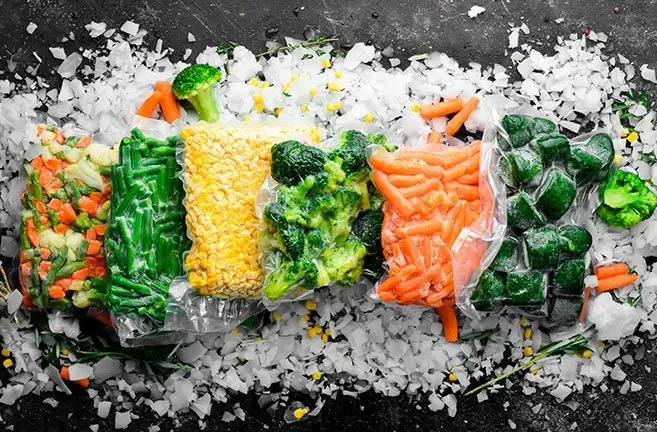 A variety of frozen vegetables are sitting on top of ice.