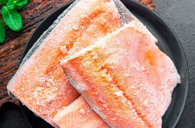 A close up of a plate of frozen fish on a table.