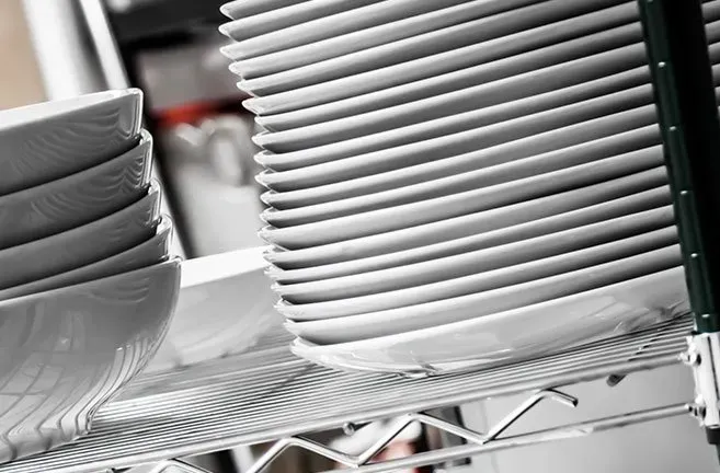 A stack of white plates and bowls on a wire rack.