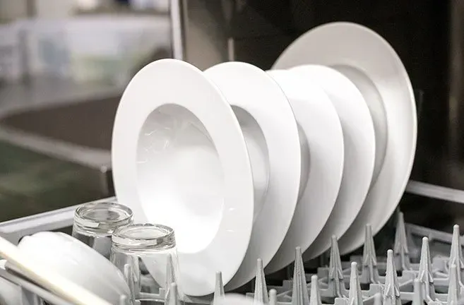 A dishwasher filled with white plates and glasses