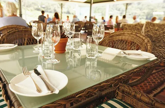 A restaurant table with plates , glasses , and silverware on it.