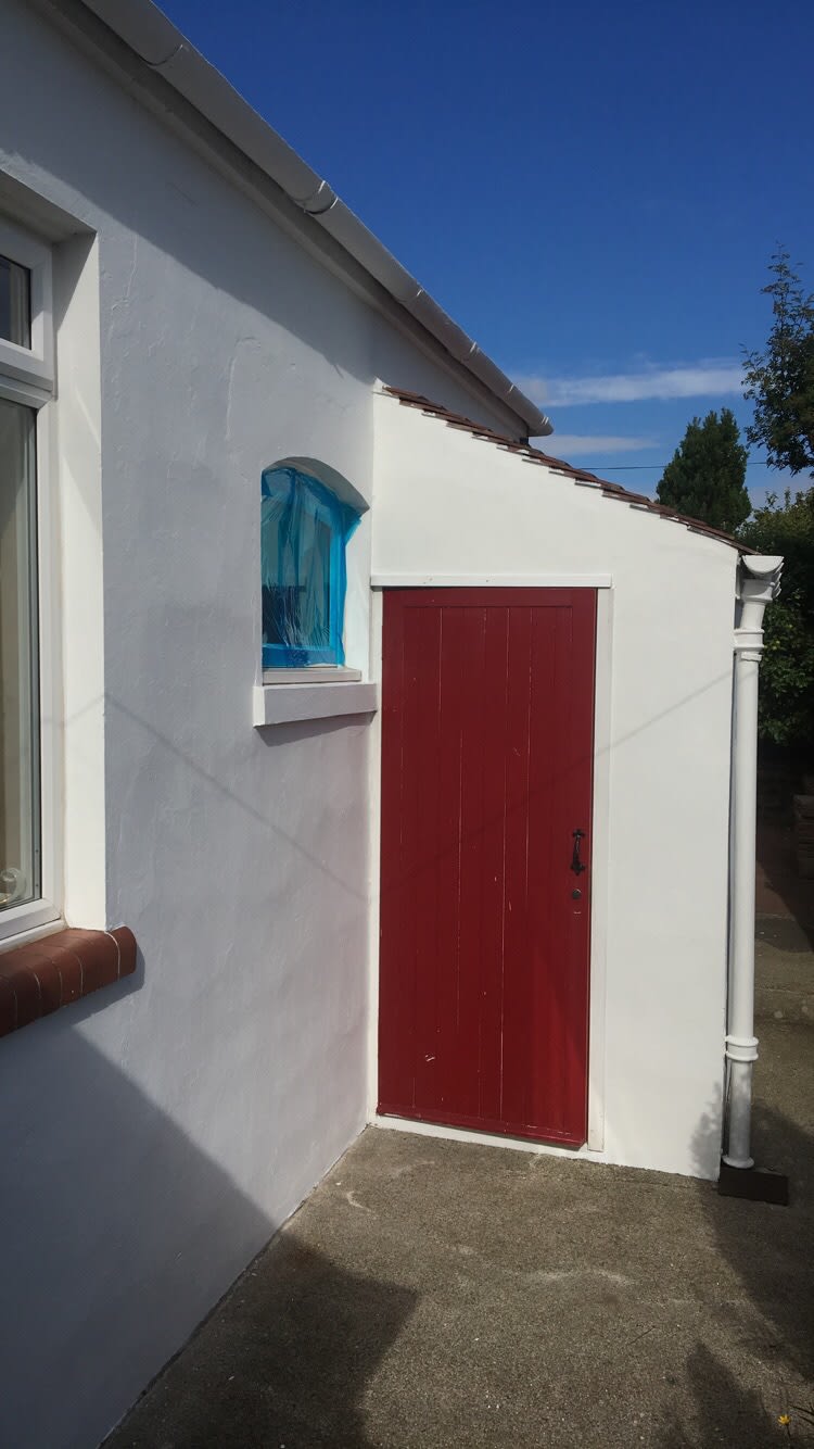 Red door on a white pebble dashed house