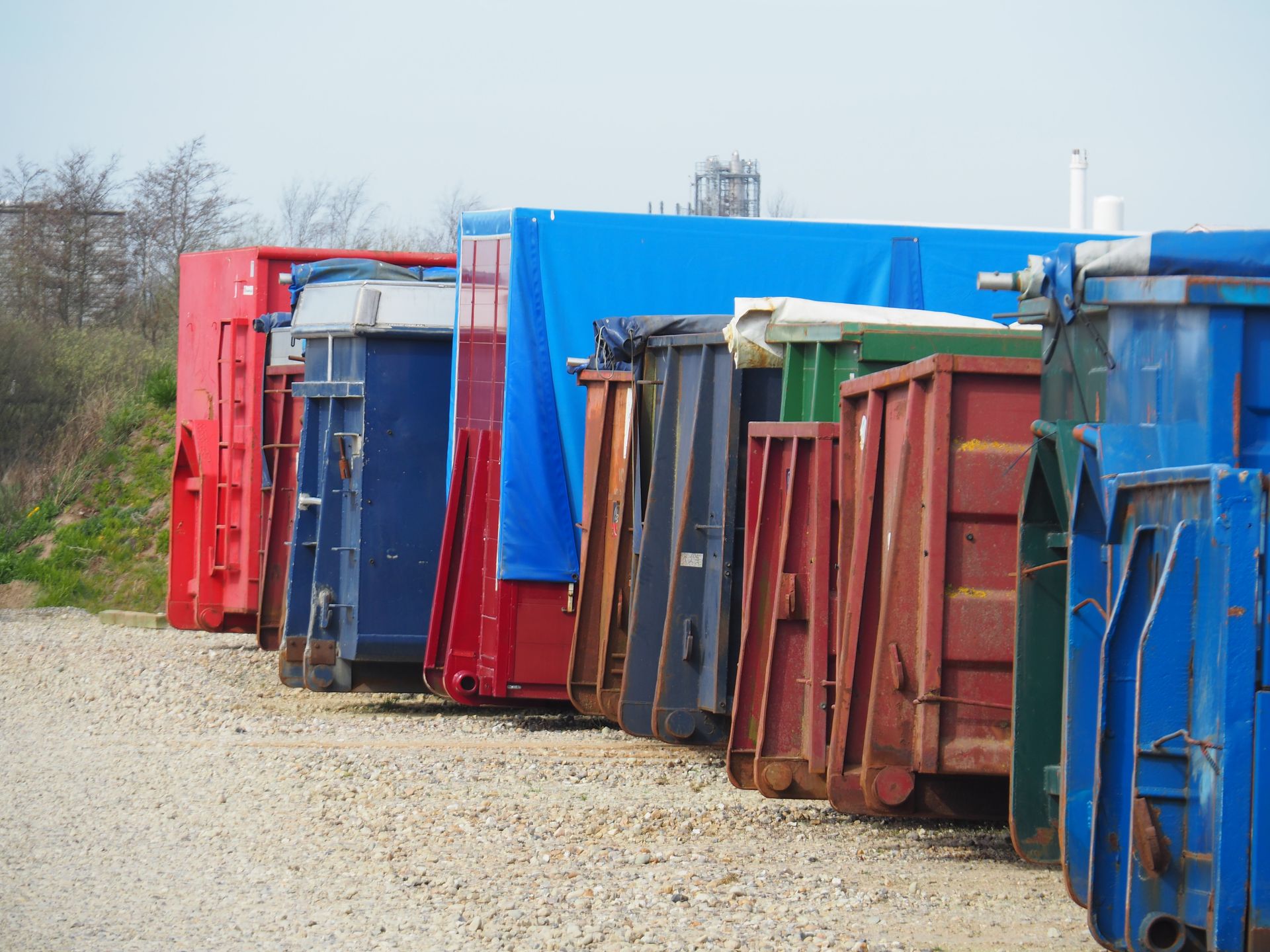 Rød Volvo lastbil og blå/rød varevogn parkeret på en grusplads med grusbunker i baggrunden.