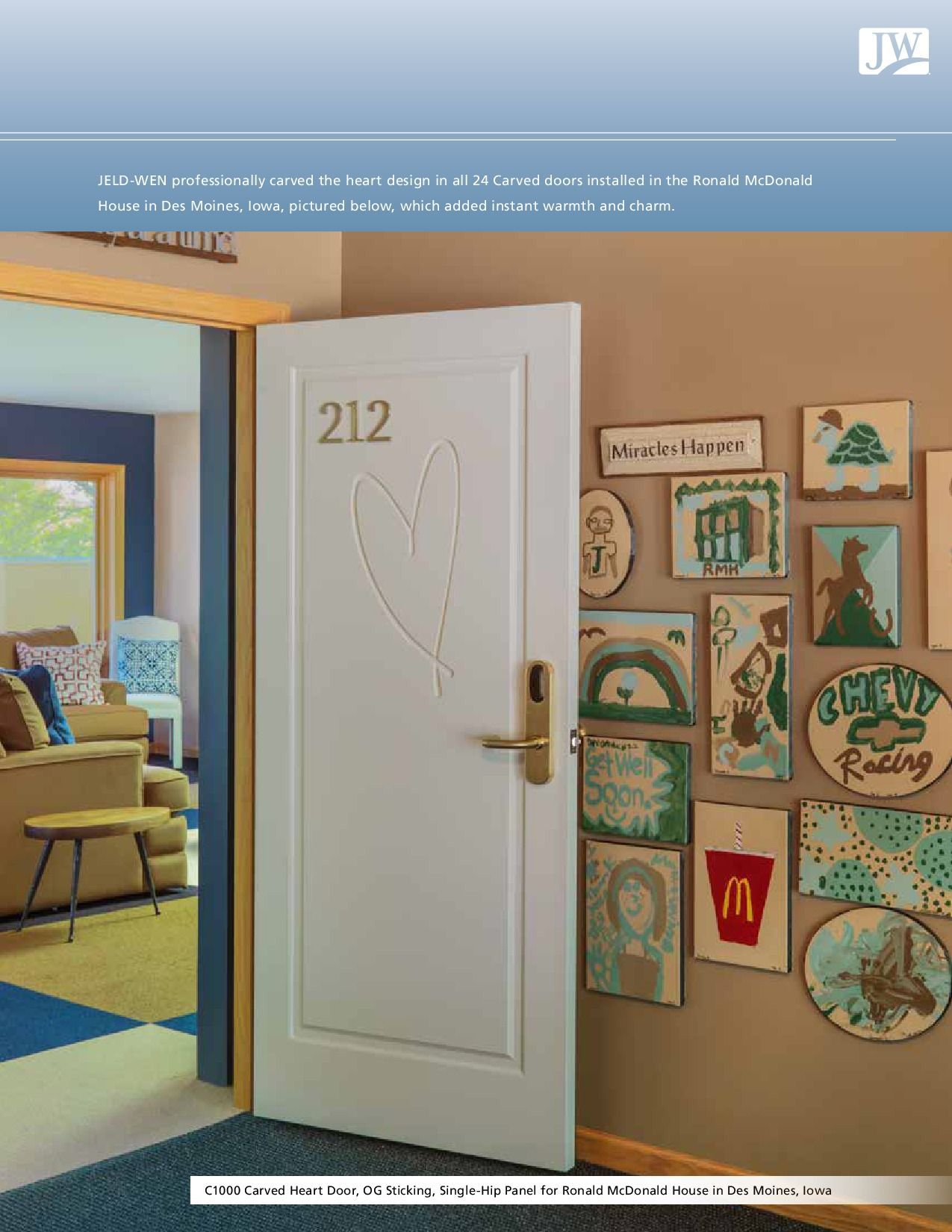 White door with a heart cut-out, adorned with artwork and leading into a room with blue and tan decor.