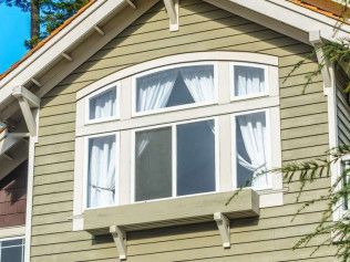 Multi-pane window with white trim on a house with green siding.
