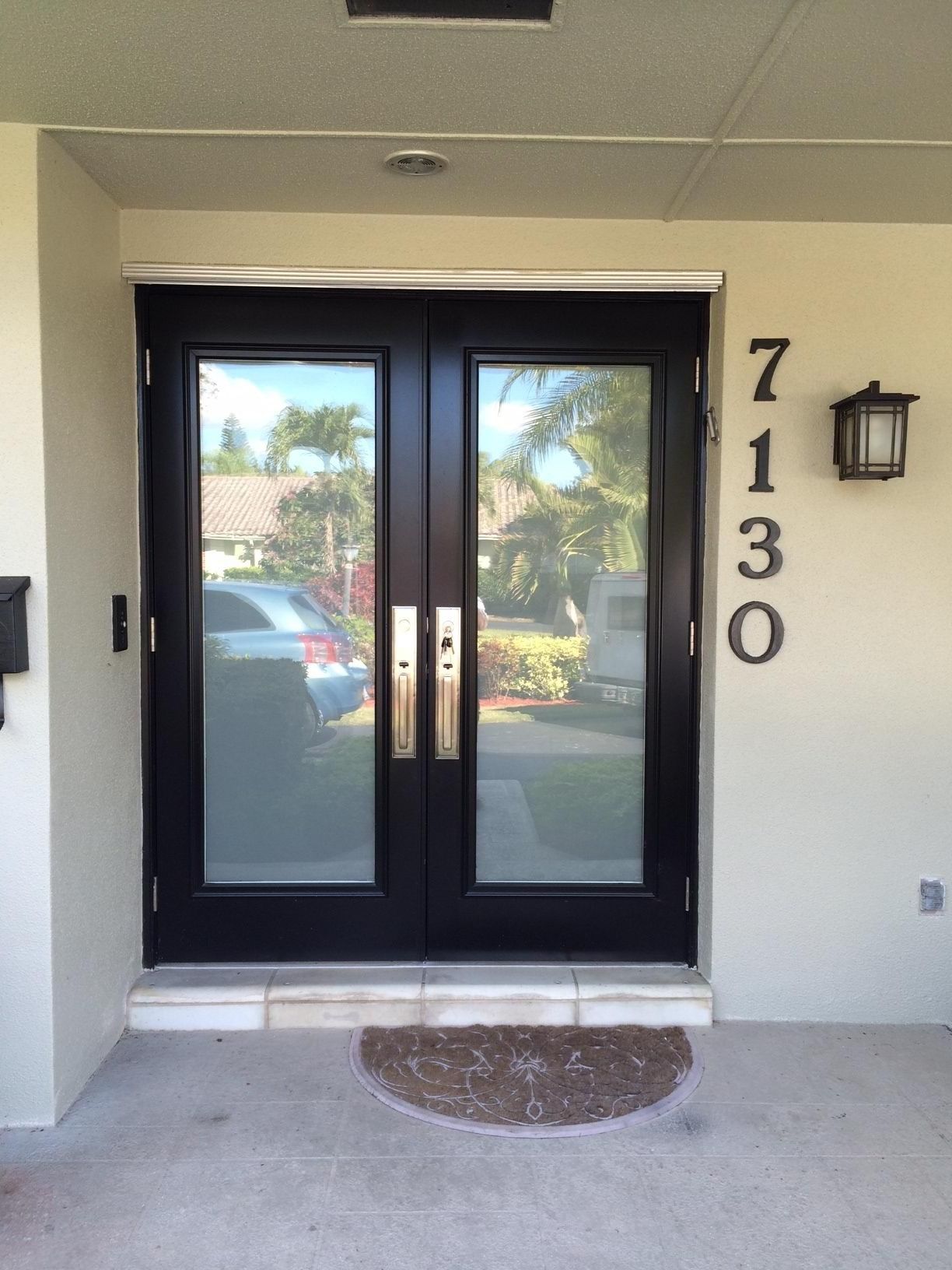 Double black doors with glass panes, brass handles, address 