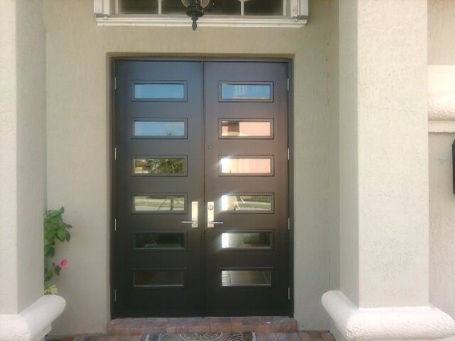 Black double doors with rectangular glass panels, set in a light beige building exterior.