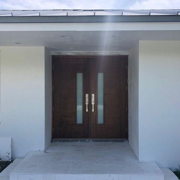 Dark double doors with glass panels and gold handles; entrance to a building.