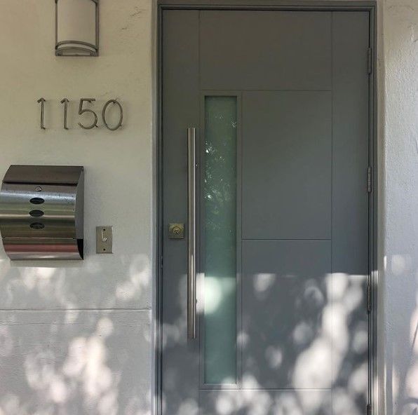 Modern gray front door with frosted glass panel, silver handle, and house number 1150.