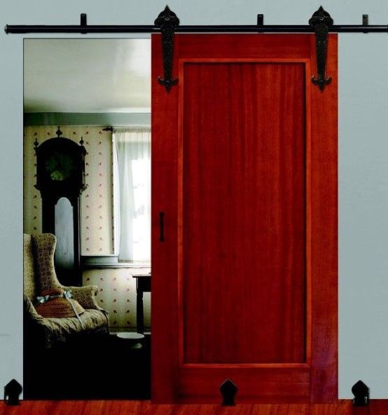 Barn door, red wood, black track and hardware. Slides open, revealing a room with a clock and chair.