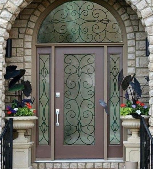 Brown front door with decorative glass and ironwork, set in a stone archway.