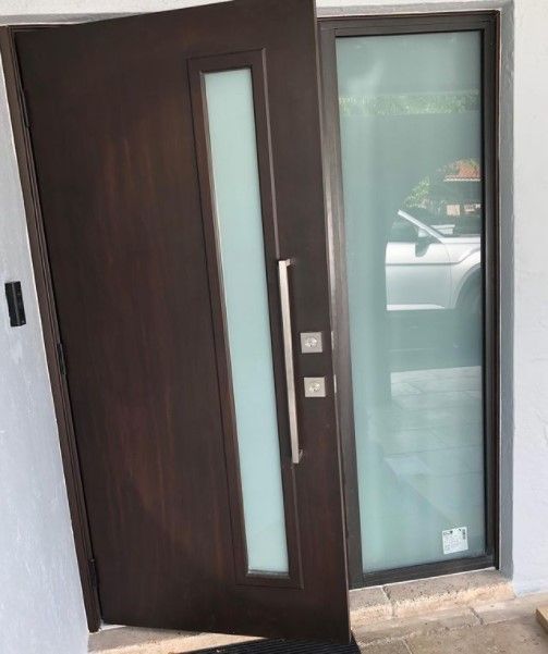 Dark brown door with frosted glass panel next to a glass pane. A car reflects in the side window.