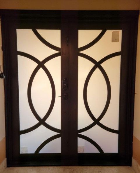 Dark brown double doors with circular, geometric black design and frosted glass panels.