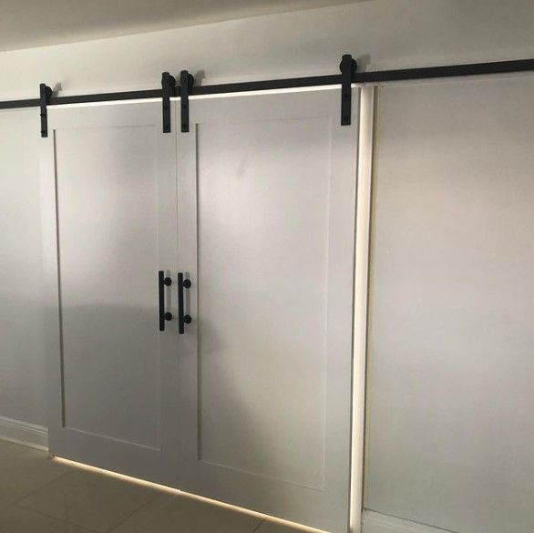 White barn doors with black hardware mounted on a black track.