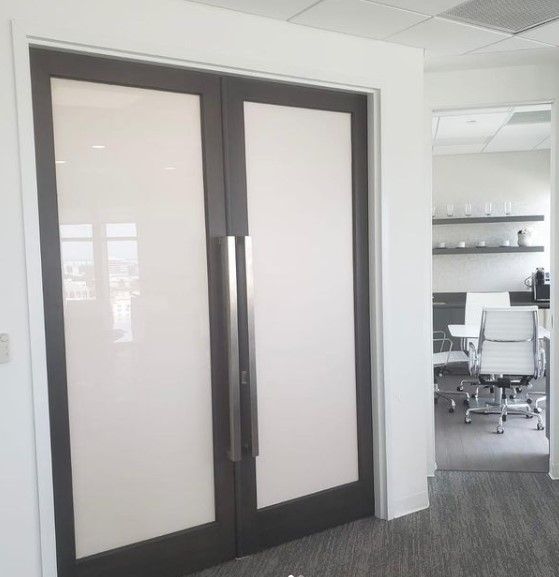 Double doors with frosted glass and dark frames lead to an office.
