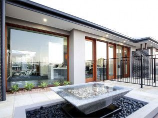 Modern patio with a fire pit, large windows, and wooden doors.